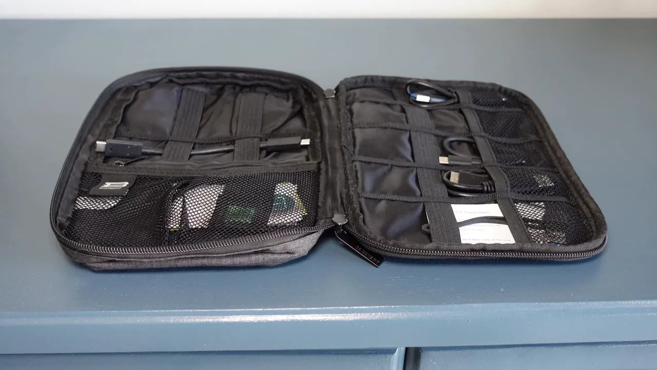 Open black electronics organizer case with multiple mesh pockets and elastic loops for cables and accessories