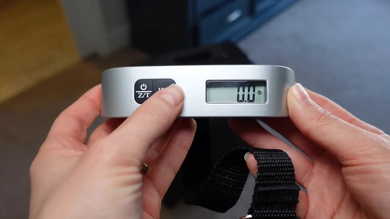 Close-up of digital luggage scale display being used with strap attached